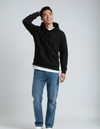 A smiling Asian man models Callahans' black Heavyweight Hoodie P2016, a fleece pullover over a white tee and blue jeans.