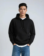 A male model wears a black Heavyweight Pullover Hood P2016 hoodie by SpectraUSA from Callahans store, with a white tee and blue jeans.